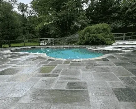 Full bluestone pool surround built by Baudi Landscaping around a curved pool in Westchester County, NY