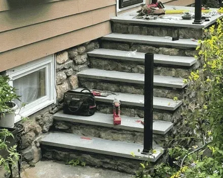 New bluestone treads set on the original fieldstone risers with new rail posts plumbed, by Baudi Landscaping