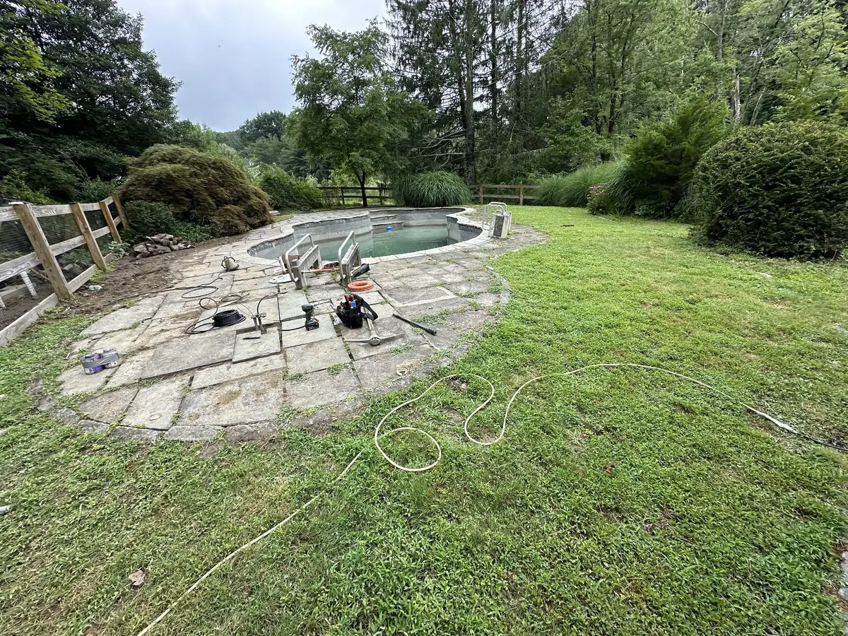Pool patio under construction on a wooded lot