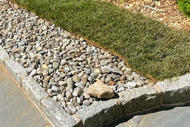 River-rock drainage swale beside a bluestone patio